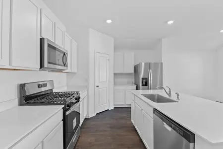 Kitchen featuring dark wood-style floors, appliances with stainless steel finishes, light countertops, and a sink