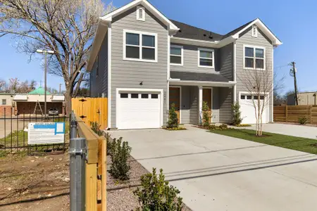 Traditional-style house featuring an attached garage, driveway, and fence