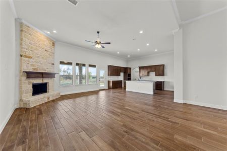 Unfurnished living room with ceiling fan, sink, dark hardwood / wood-style floors, crown molding, and a fireplace