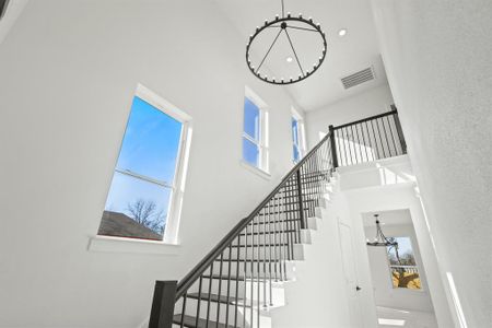 Stairway featuring a towering ceiling and a chandelier