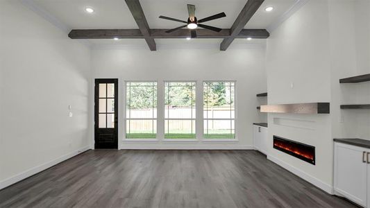 Living area has coffered wood beam ceiling and inviting electric fireplace