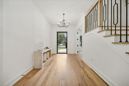 Foyer entrance with light hardwood floors and a chandelier