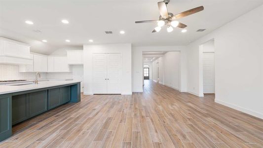 Kitchen featuring decorative backsplash, white cabinets, light hardwood / wood-style floors, and ceiling fan