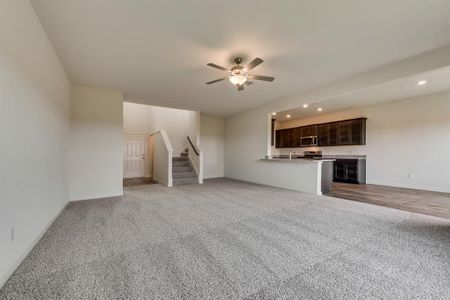 Unfurnished living room featuring light colored carpet, sink, and ceiling fan