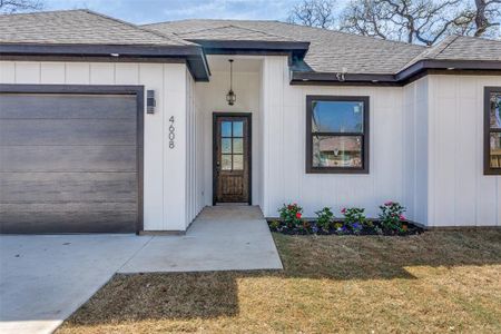 Entrance to property featuring a yard, board and batten siding, a shingled roof, and a garage