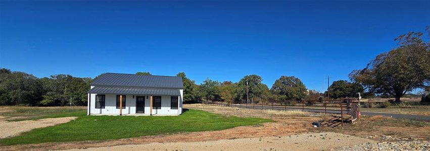 Covered porches on front and back. Pipe fence and gate on one side of the land