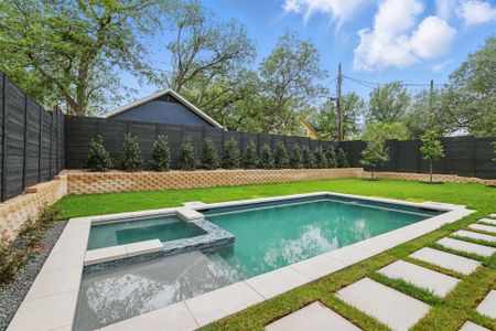 View of pool with a fenced backyard and a pool with connected hot tub