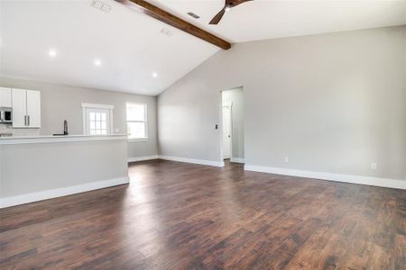 Unfurnished living room with vaulted ceiling with beams, dark hardwood / wood-style floors, and ceiling fan