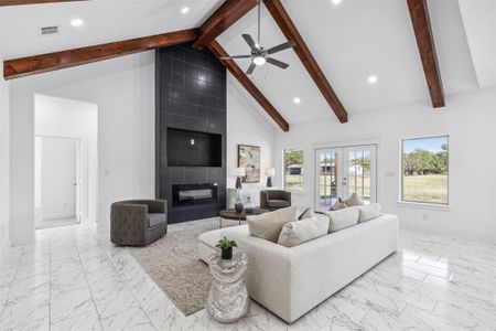 Living room with ceiling fan, plenty of natural light, a tile fireplace, and light tile patterned floors