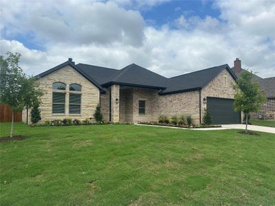 French country inspired facade featuring a garage and a front lawn