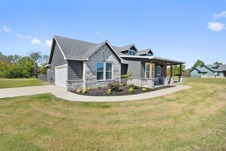 View of front of home featuring a front lawn, covered porch, and a garage