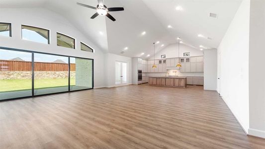 Unfurnished living room with high vaulted ceiling, ceiling fan, and light hardwood / wood-style flooring