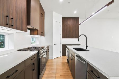 Kitchen featuring sink, light hardwood,  wall chimney range hood, and appliances with stainless steel finishes