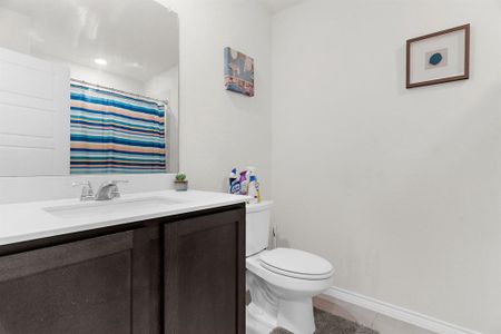 Full bath featuring baseboards, toilet, vanity, a shower with curtain, and tile patterned flooring Full bath featuring baseboards, toilet, vanity, a shower with curtain, and tile patterned flooring