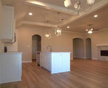 Kitchen featuring white cabinetry, decorative light fixtures, a center island with sink, appliances with stainless steel finishes, and ceiling fan with notable chandelier