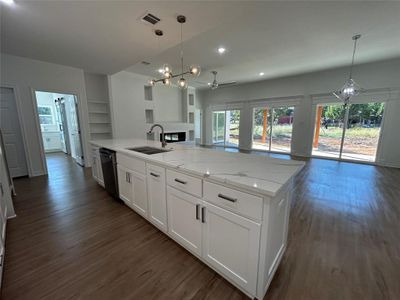 Kitchen with a large island with sink, stainless steel appliances, sink, white cabinetry, and dark hardwood / wood-style flooring