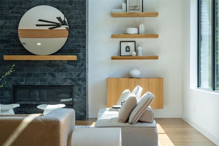 Sitting room featuring light wood-type flooring, ceiling fan, and a large fireplace