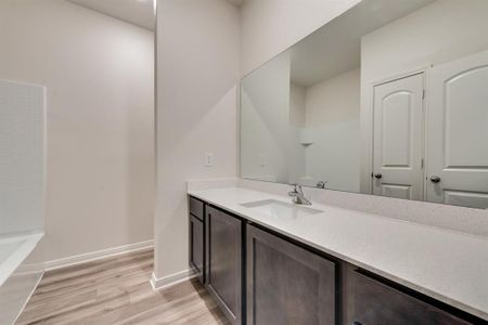 Bathroom with bathing tub / shower combination, vanity, and hardwood / wood-style flooring