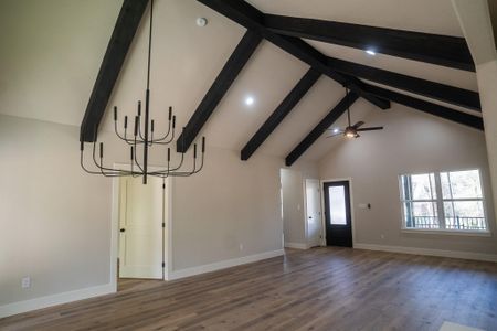 Unfurnished living room featuring high vaulted ceiling, wood finished floors, beamed ceiling, and a chandelier