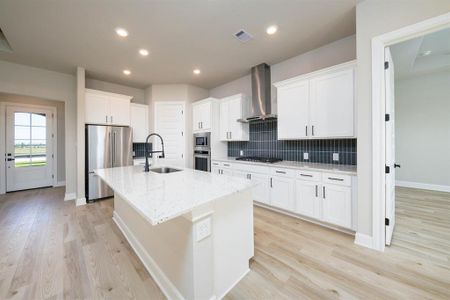 The kitchen island serves as a multifunctional hub, providing a seamless transition between the kitchen and family room, allowing for easy interaction and socializing while cooking or entertaining.