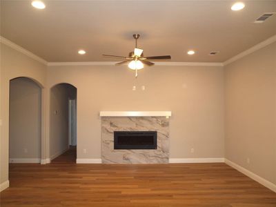 Unfurnished living room featuring hardwood / wood-style flooring, ornamental molding, and a high end fireplace