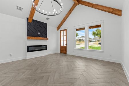 Unfurnished living room featuring beamed ceiling, a fireplace, high vaulted ceiling, and light parquet floors