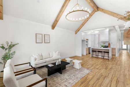 Living room with a chandelier, beamed ceiling, light wood-type flooring, and high vaulted ceiling