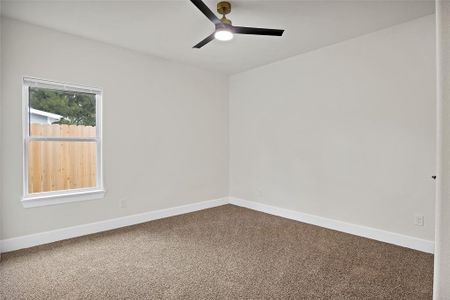 Carpeted empty room featuring ceiling fan