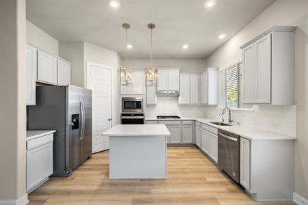 Outfitted with stainless steel appliances, including a gas range and double-door refrigerator, this kitchen combines style and efficiency.