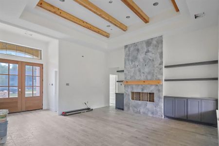 The tray ceiling design adds depth and dimension, artfully accented by rustic wood beams, drawing the eye upward and creating an open, airy ambiance throughout the space.