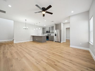 Unfurnished living room featuring ceiling fan with notable chandelier, light hardwood / wood-style floors, and sink