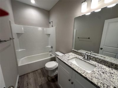 Full bathroom with vanity, toilet, hardwood / wood-style floors, and shower / washtub combination