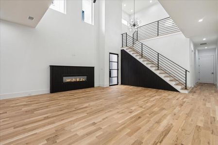 Unfurnished living room featuring a high ceiling, an inviting chandelier, and light wood-type flooring