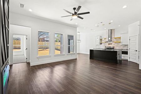 Unfurnished living room with baseboards, visible vents, dark wood-type flooring, a sink, and recessed lighting