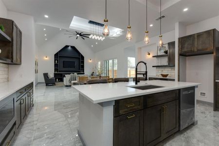 Kitchen with decorative light fixtures, an island with sink, decorative backsplash, ceiling fan, and sink