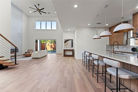 Kitchen with decorative backsplash, a kitchen bar, kitchen peninsula, light hardwood / wood-style flooring, and decorative light fixtures