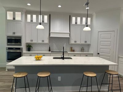 Kitchen with appliances with stainless steel finishes, hanging light fixtures, and a kitchen island with sink