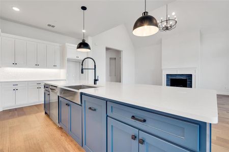 Kitchen featuring white cabinets, sink, an island with sink, and light hardwood / wood-style floors