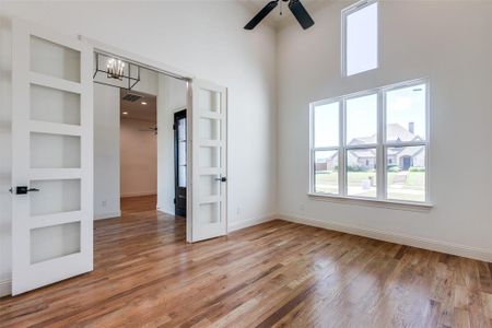 Spare room featuring ceiling fan with notable chandelier, a high ceiling, hardwood / wood-style floors, and built in features