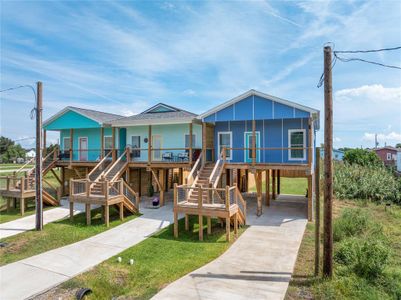 You're looking at the street view of the blue, elevated beach-style house on a raised foundation with a spacious deck and outdoor staircase.