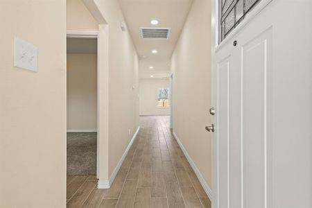 Corridor featuring wood finish floors, visible vents, baseboards, and recessed lighting