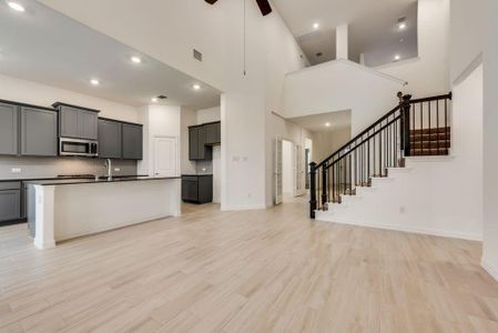 Kitchen featuring a high ceiling, a center island with sink, light hardwood / wood-style flooring, ceiling fan, and gray cabinets