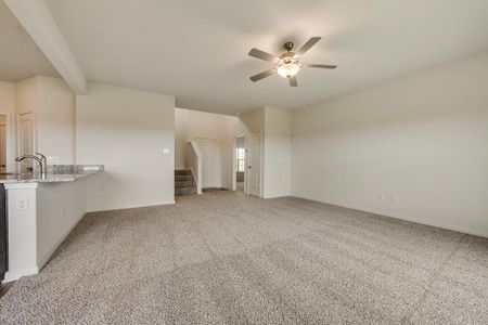 Unfurnished living room with carpet, ceiling fan, and sink