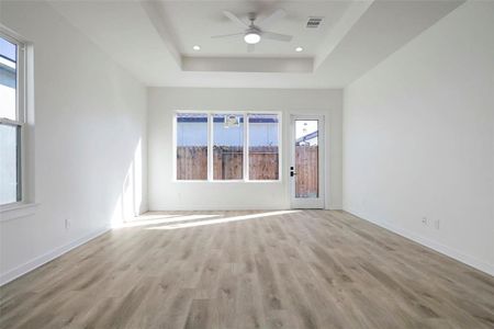 A living room with a wood floor and a ceiling fan. The room also features a window, molding, and laminate flooring.