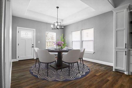 Dining room featuring dark hardwood / wood-style floors, an inviting chandelier, and a tray ceiling