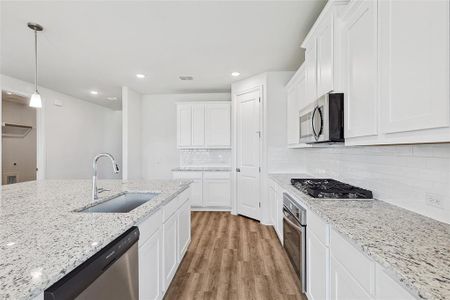 Kitchen featuring white cabinetry, sink, appliances with stainless steel finishes, light hardwood / wood-style flooring, and backsplash