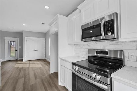 Kitchen with stainless steel appliances, white cabinets, and dark wood-type flooring