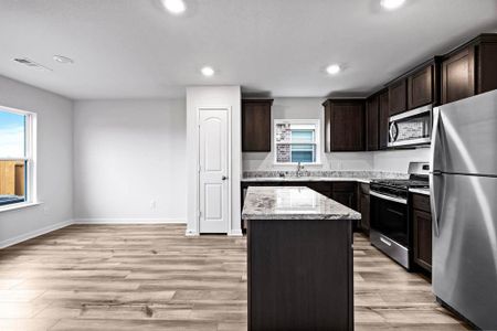 Kitchen with stainless steel appliances, a healthy amount of sunlight, light hardwood / wood-style floors, and a kitchen island