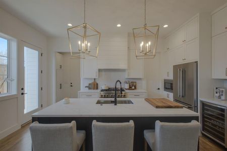 Kitchen with a kitchen island with sink, sink, beverage cooler, and stainless steel appliances