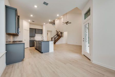 Kitchen featuring light wood-type flooring, ceiling fan, decorative backsplash, sink, and a center island with sink